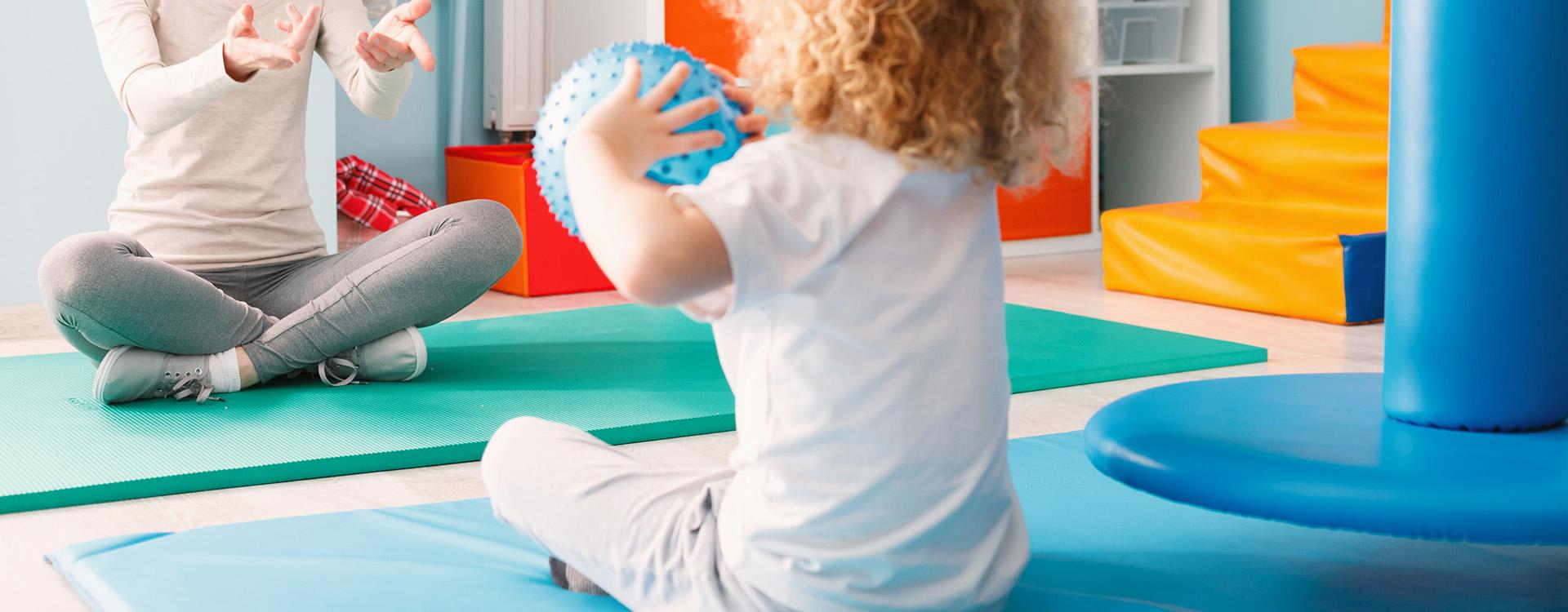 Small boy with ball in occupational therapy setting